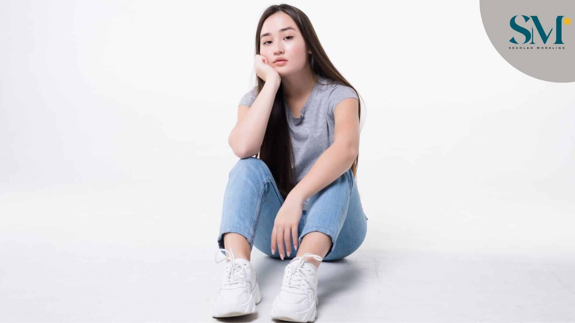Bored asian woman sitting on floor isolated on white wall