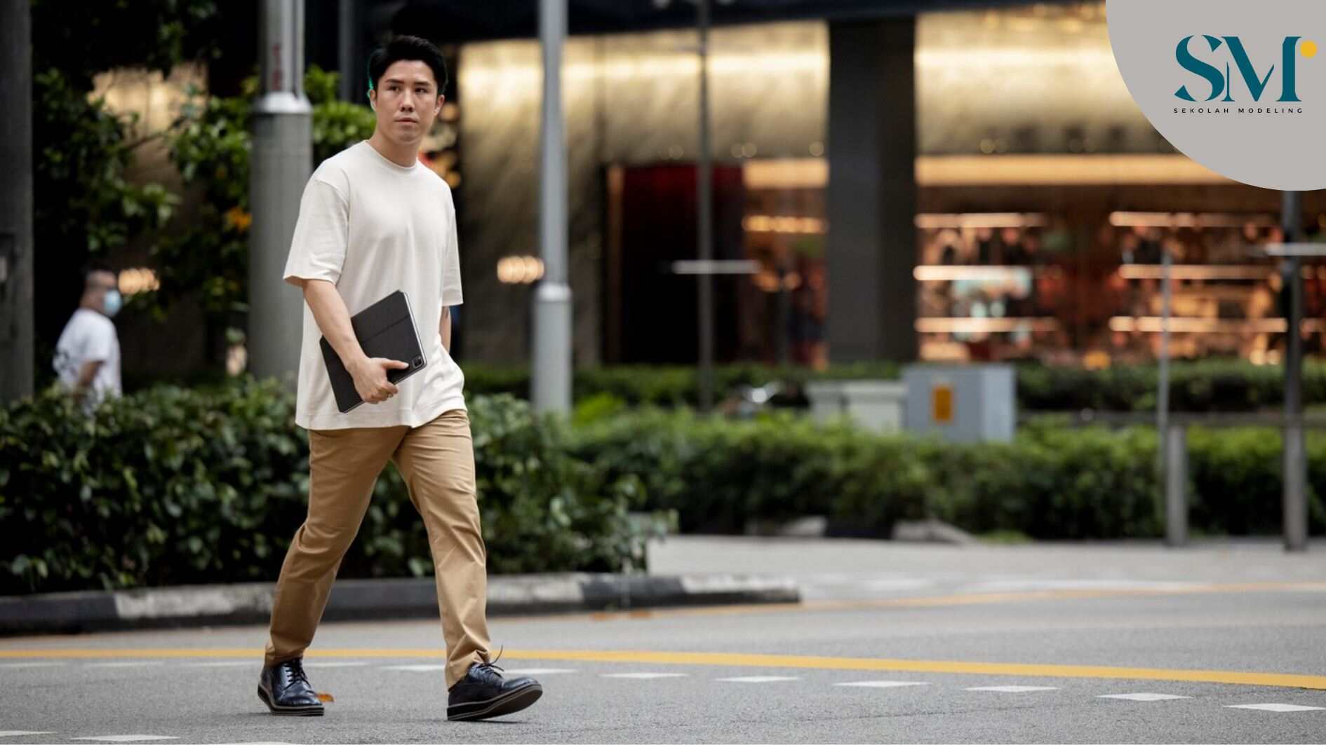 Portrait of asian man crossing the street in the city while holding laptop