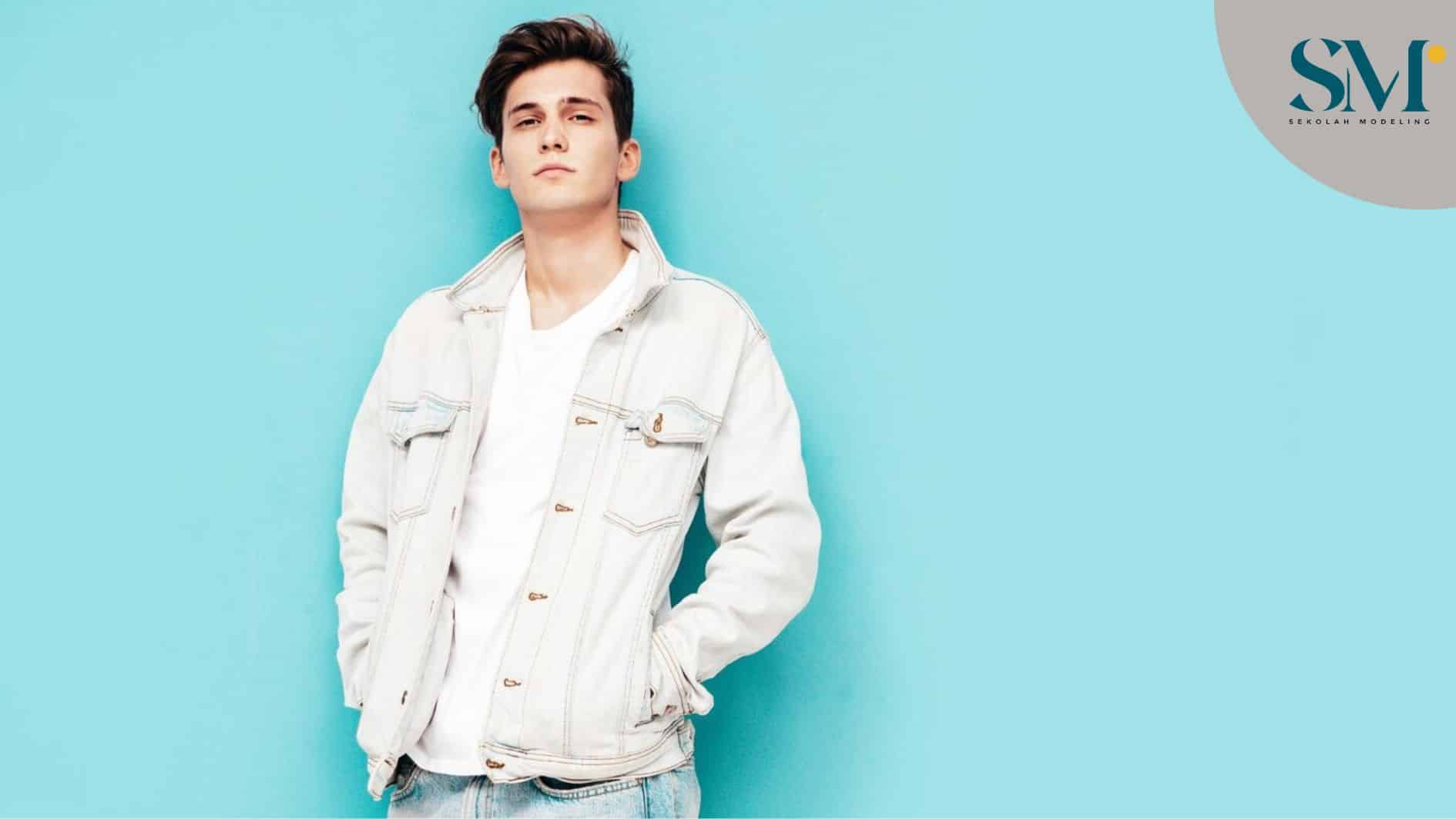 Portrait of handsome confident stylish hipster lambersexual modelMan dressed in jacket and jeans Fashion male posing in studio near blue wall