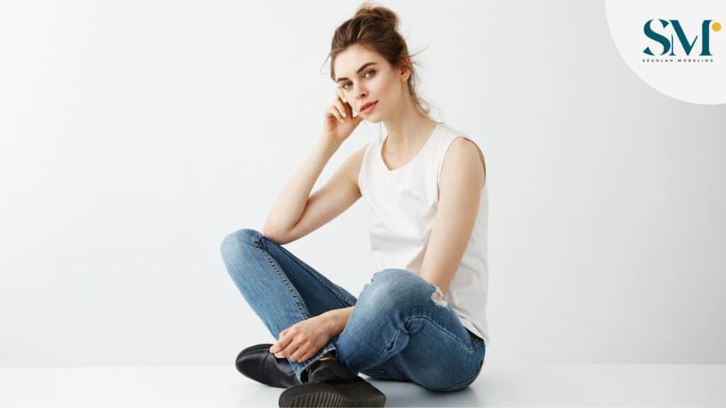 Young beautiful brunette woman with bun smiling sitting over white background