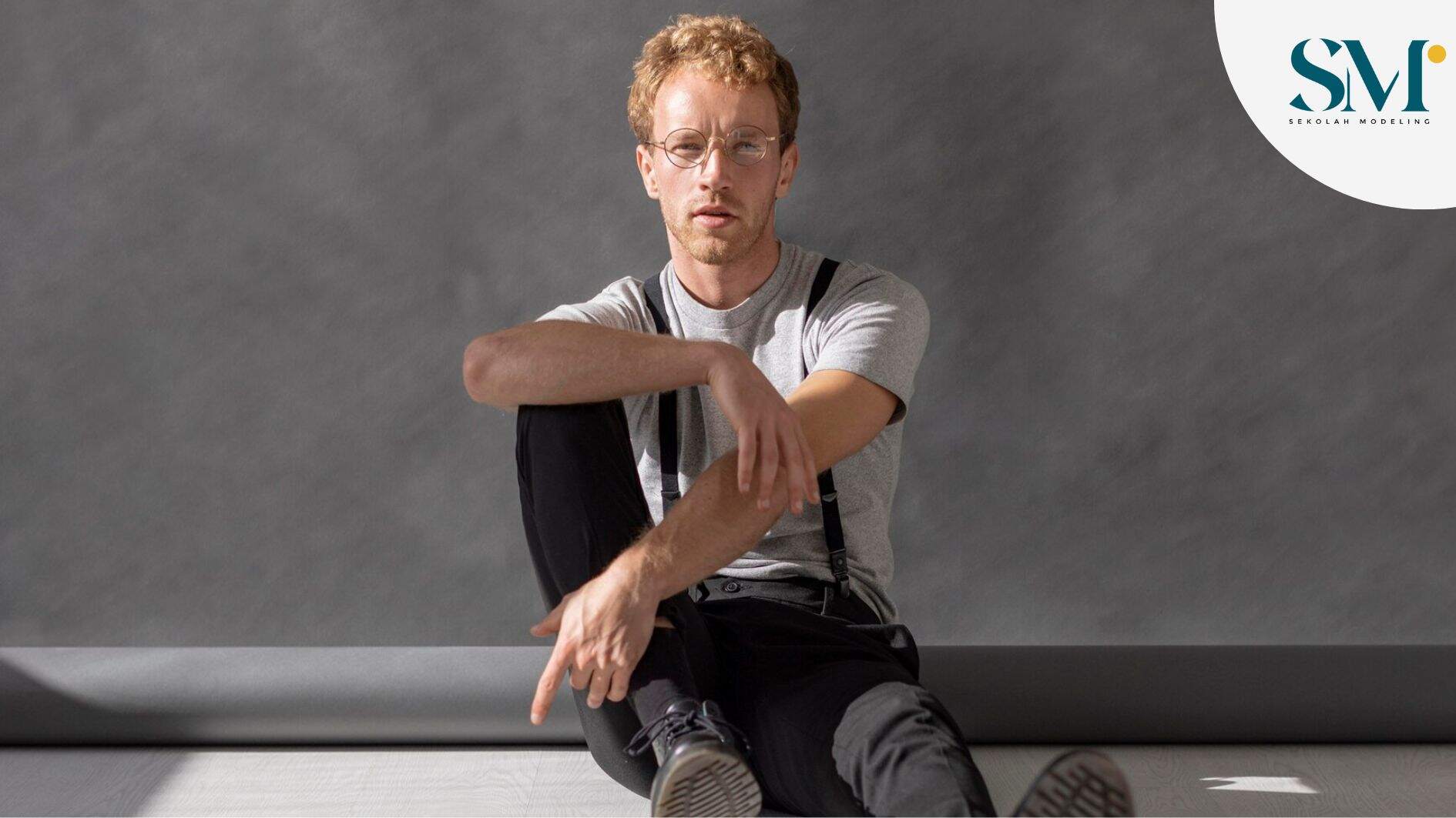 man wearing glasses sitting on the floor